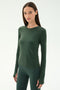 A woman poses against a white background, wearing the SPLITS59 Airweight Lite LS Waist Length top in Military, paired with matching leggings—both crafted from stretchy spandex fabric.