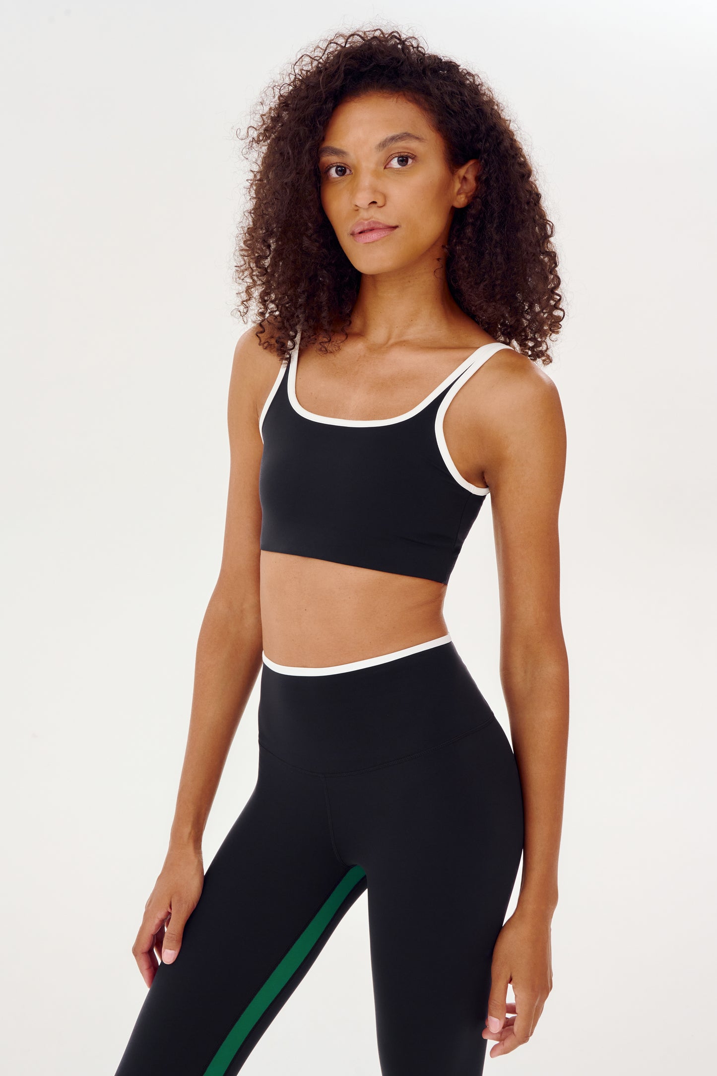 A woman wearing a Cait Rigor Bra in Black/White and matching leggings, designed for high impact workouts by SPLITS59.