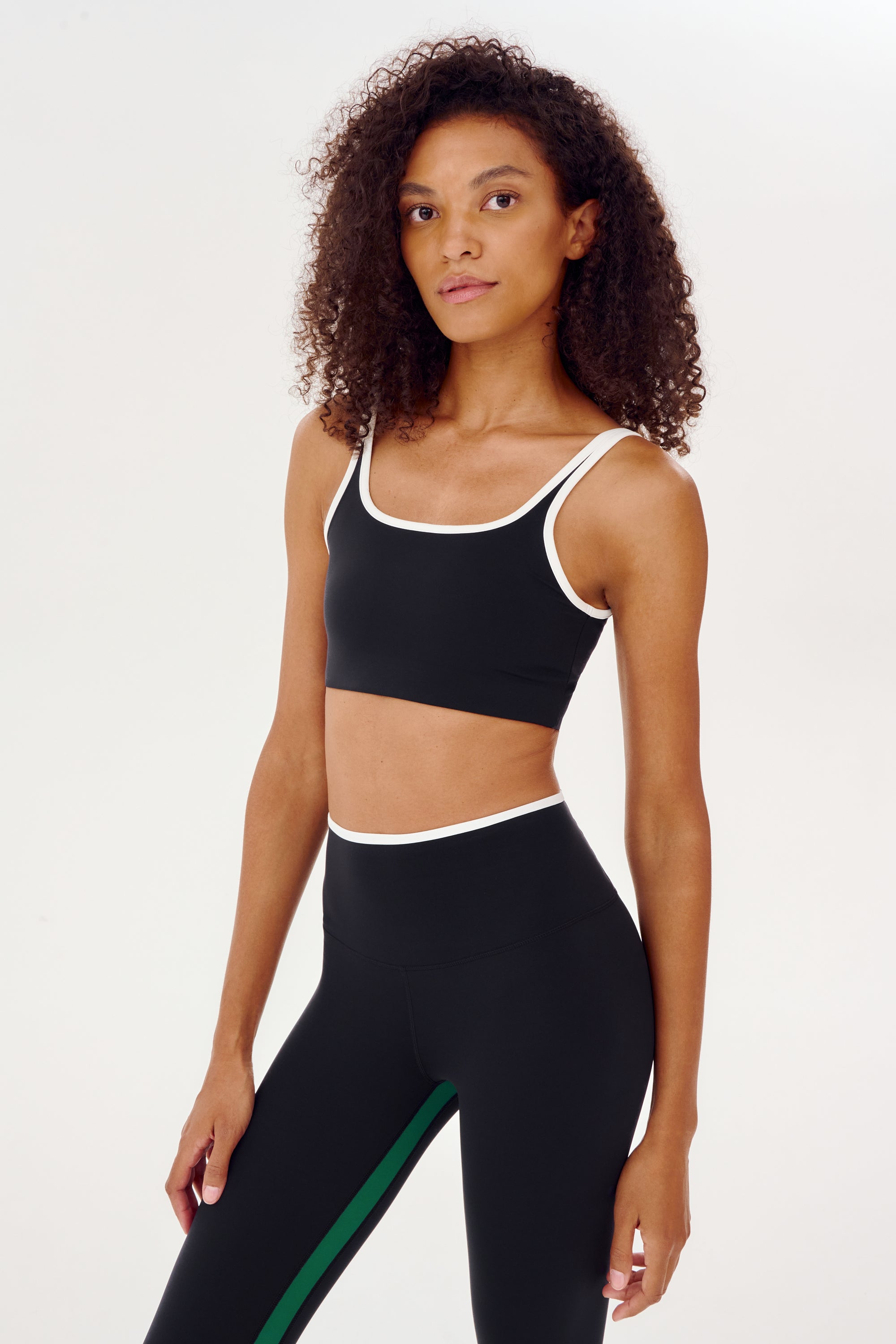 A woman wearing a Cait Rigor Bra in Black/White and matching leggings, designed for high impact workouts by SPLITS59.