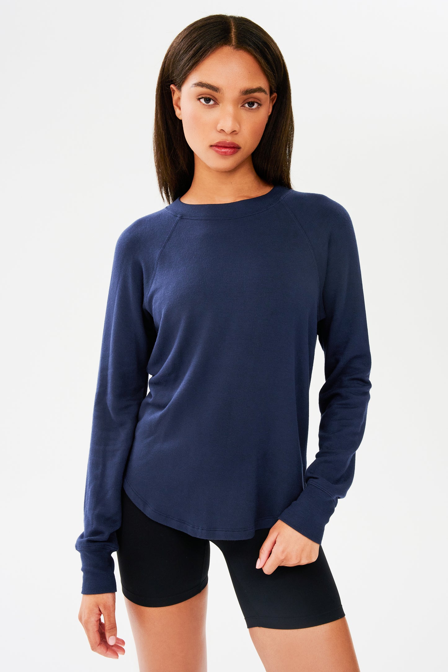Front shot of woman with dark straight hair, wearing dark blue sweatshirt with black shorts 