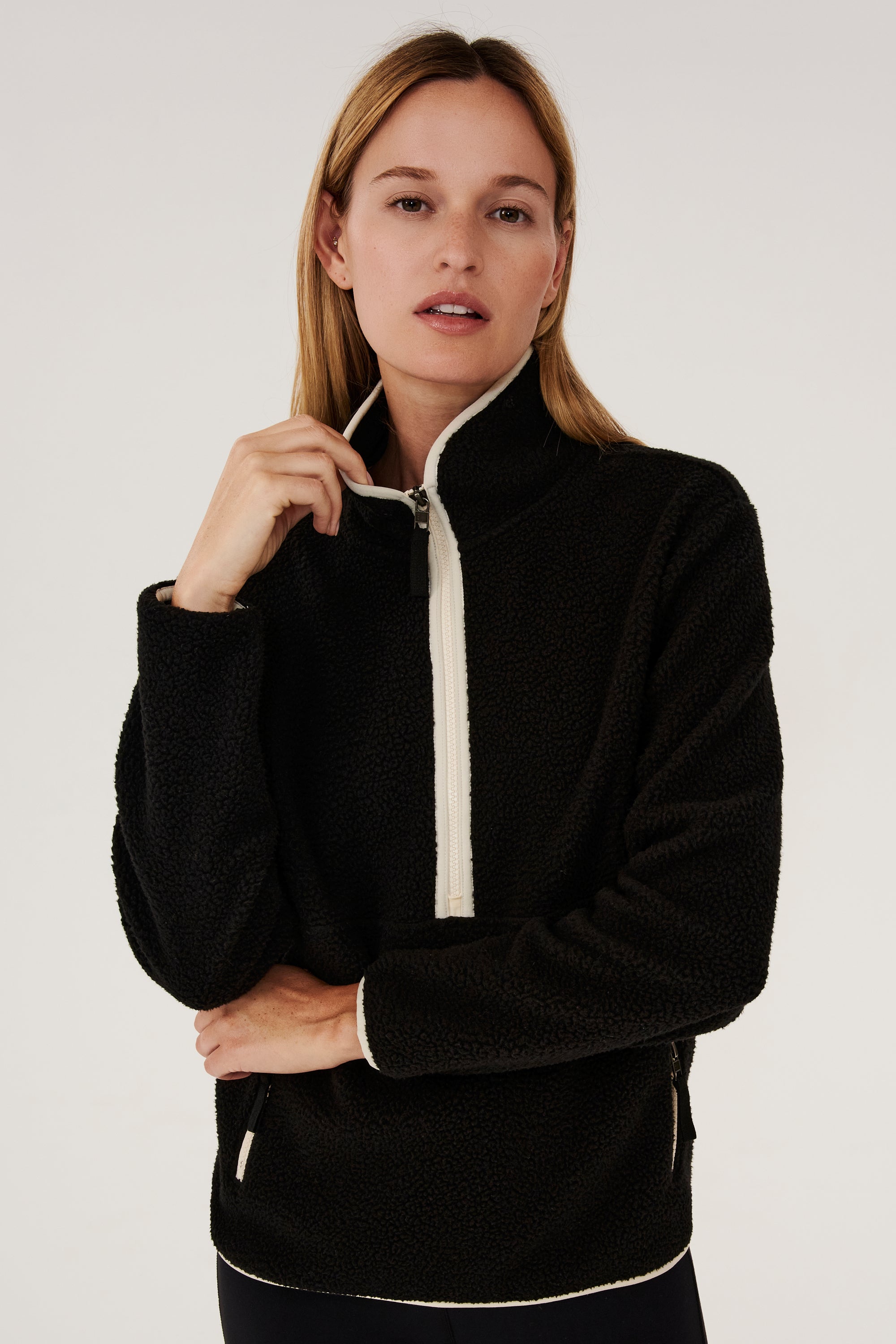 A woman wearing a SPLITS59 Libby Sherpa Half Zip in Black/Creme.