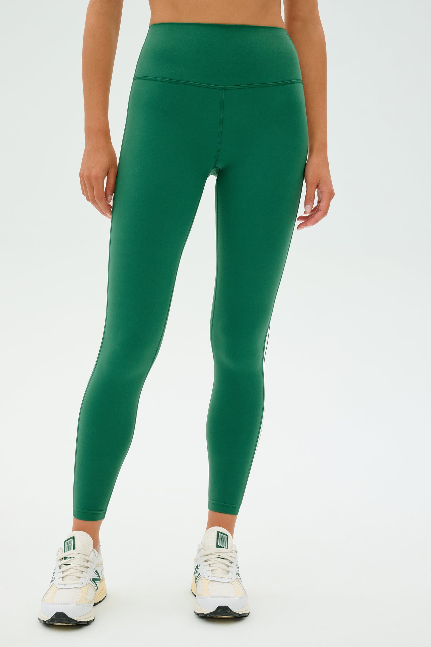 A person is sporting the SPLITS59 Clare High Waist Rigor 7/8 in Arugula/White paired with white sneakers, ideal for gym workouts thanks to its high-performance Rigor fabric.