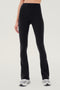 Front view of woman wearing black high waist below ankle length legging with wide flared bottoms. Paired with white and gray shoes.