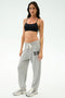 A person stands against a plain background wearing a black crop top, white sneakers, and the SPLITS59 Andie Oversized Fleece Varsity 59 Sweatpant in Heather Grey/59—perfect for cool weather workouts.