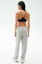 Woman standing with her back to the camera, wearing a black sports bra, SPLITS59 Andie Oversized Fleece Varsity 59 Sweatpant in Heather Grey/59, and white sneakers—ideal for cool-weather workouts against a plain light background.