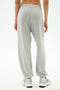 A person wearing SPLITS59 Andie Oversized Fleece Varsity 59 Sweatpant in Heather Grey/59 and white sneakers, shown from the back against a plain white background—ideal for cool weather workouts.