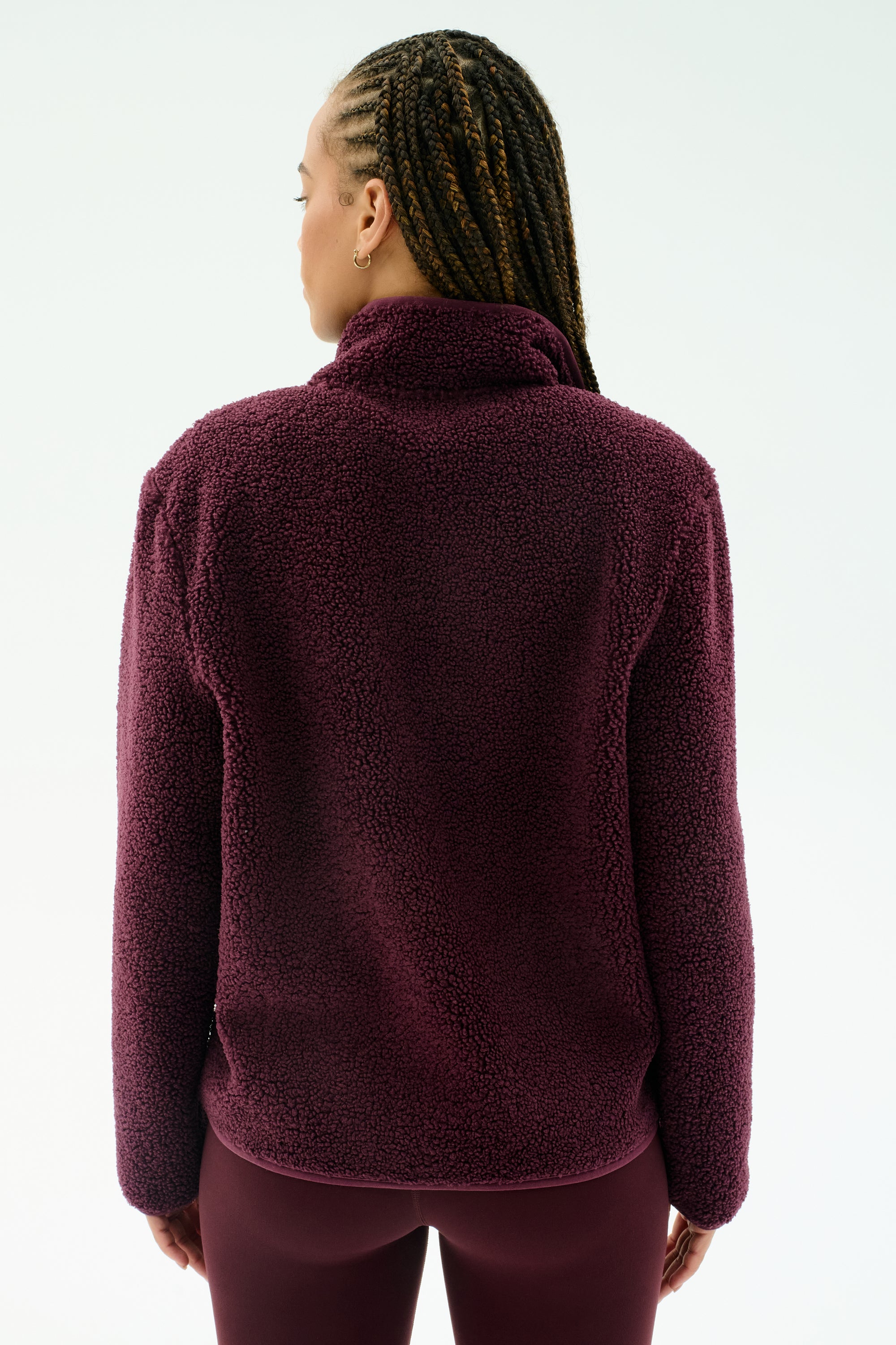 Individual with braided hair wears the SPLITS59 Harris Sherpa Jacket in Dark Cherry, crafted from soft polyester, seen from the back against a plain light background.