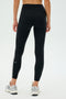 Person wearing SPLITS59 Clare High Waist Rigor 7/8 - Black/White leggings and white sneakers, standing against a plain background.