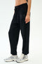 A person wears the SPLITS59 Andie Oversized Fleece Varsity 59 Sweatpant - Black/59, featuring a "59" print on the left thigh, paired with white sneakers and a crop top—perfect for cool weather workouts—against a white background.