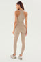 Woman in beige workout attire, including a racerback tank top and Airweight Super High Waist 7/8 - Latte leggings by SPLITS59, standing with her back facing the camera against a plain white background. Perfect for hot yoga sessions.