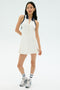A woman stands against a light background wearing the SPLITS59 Austin Rigor Dress in White/Indigo, paired with striped socks and silver sneakers.