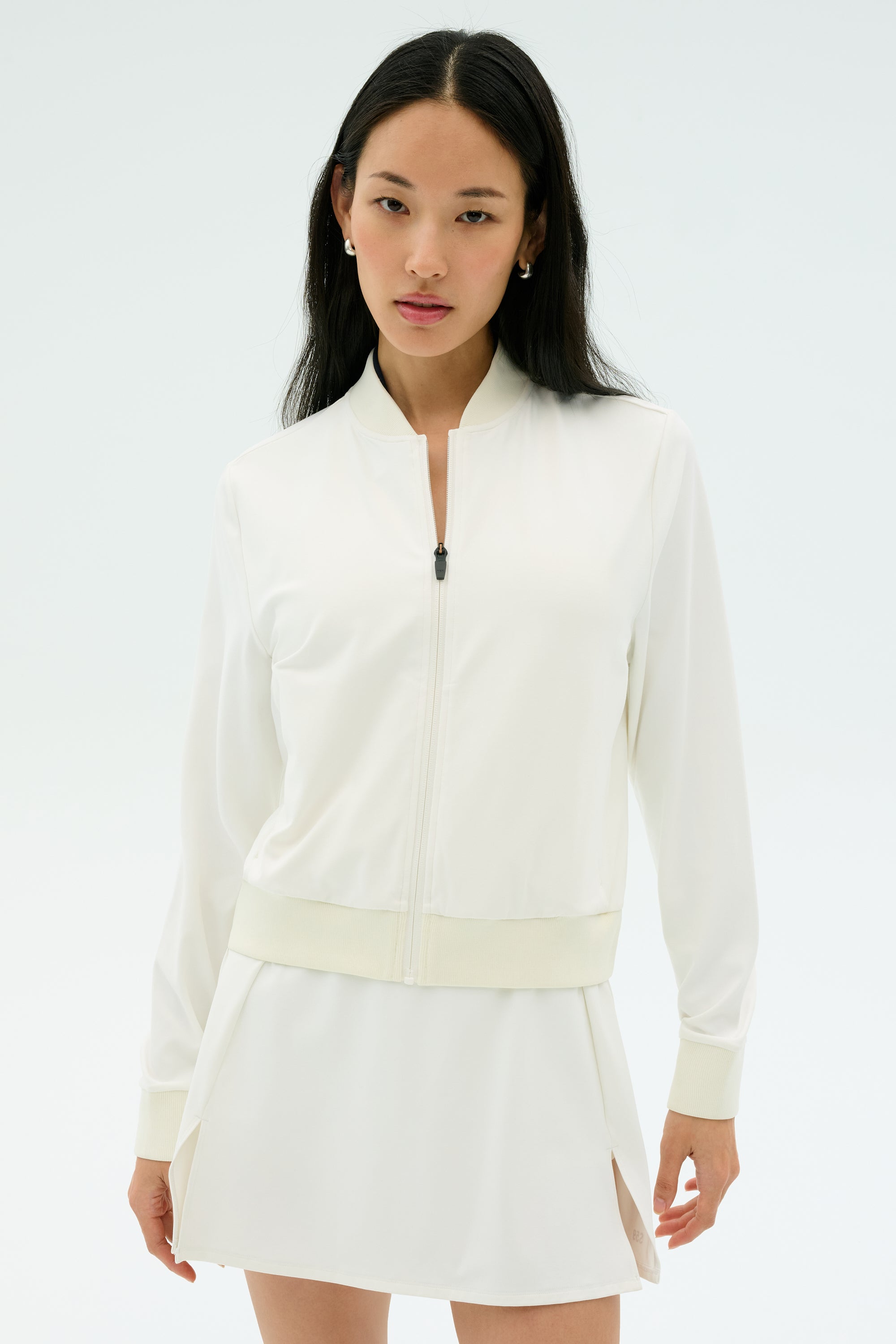 A woman wearing the SPLITS59 Airweight Bomber Jacket in white stands against a plain light background, looking at the camera.