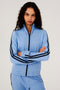 A woman wearing a Splits59 Fox Techflex Jacket in Jacinthe/Indigo with black stripes, warming up.