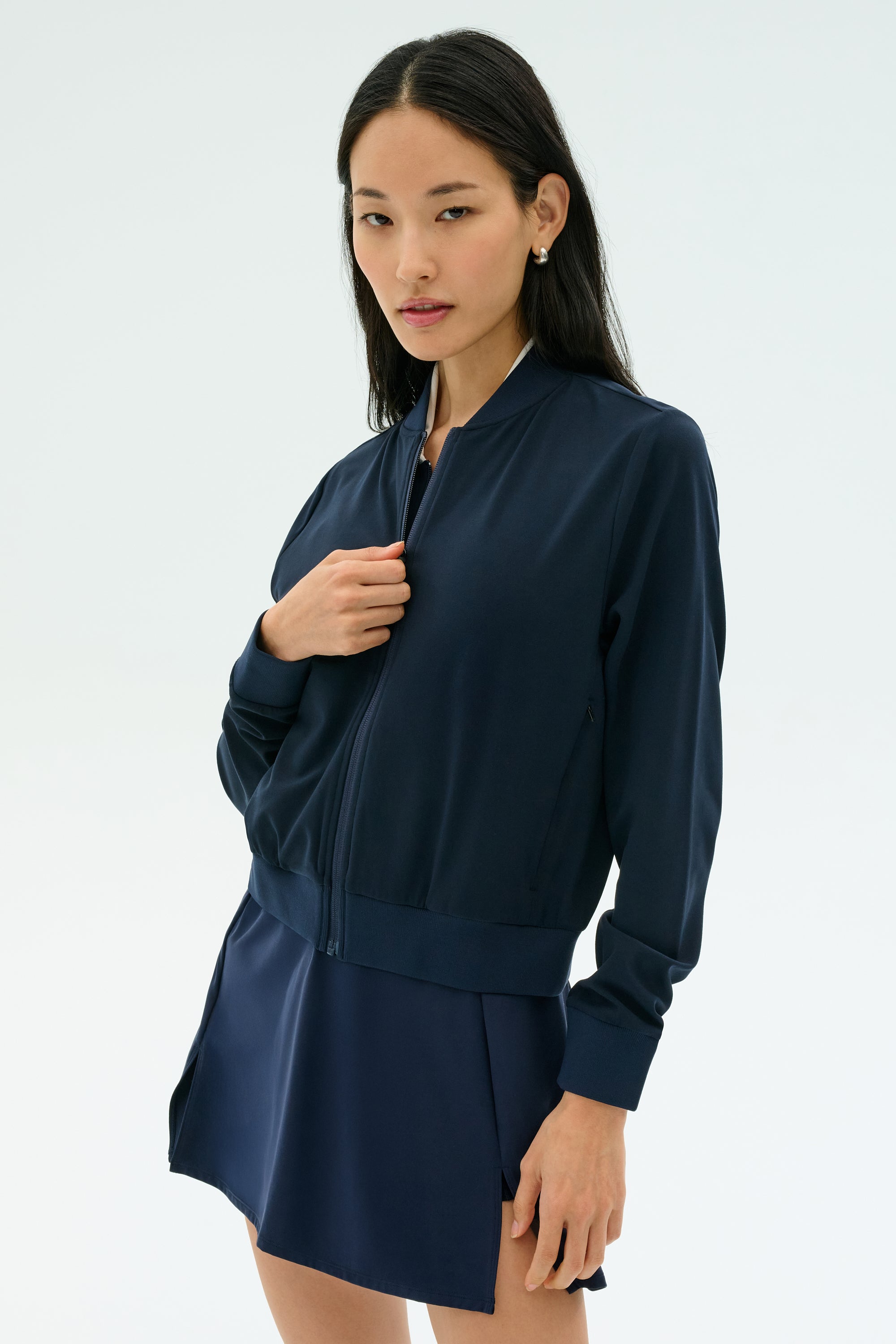 A woman wearing the SPLITS59 Airweight Bomber Jacket in Indigo stands against a plain light background, looking at the camera.
