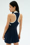 A woman with long dark hair wears the SPLITS59 Austin Rigor Dress in Indigo/White, standing slightly turned away in a minimalist studio.