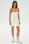 A person is wearing the Monah Rigor Dress in White/Arugula by SPLITS59, paired with sneakers, standing on a light background.