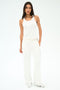 A woman stands against a plain white background wearing the SPLITS59 Mel Airweight Lite Tank in white, paired with white wide-leg pants and white sneakers.