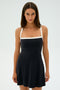 A person with long dark hair wears the Monah Rigor Dress by SPLITS59, featuring white straps and a square neckline, standing against a plain white background.