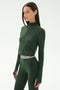 A woman wearing the SPLITS59 Stevie Active Rib Half Zip in Heather Military stands against a plain white background.