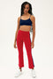 A woman stands against a plain background wearing SPLITS59’s Raquel High Waist Crop pants in Pirate Red/Indigo, featuring navy side stripes and 4-way stretch fabric, styled with a navy crop top and white sneakers.
