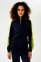 A woman warming up in a luxurious SPLITS59 Fox Techflex Jacket - Indigo/Chartreuse.