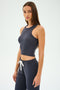 Someone is wearing the Kiki Rib Crop Tank in Graphite by SPLITS59, paired with matching pants featuring a white drawstring, against a plain background. Made in Los Angeles.