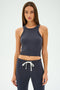 A woman with long hair, wearing a SPLITS59 Kiki Rib Crop Tank in graphite and matching jogger pants, stands against a plain background.