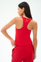 A woman wearing the SPLITS59 Mel Airweight Lite Tank in Pirate Red stands with her back to the camera, looking to the side against a plain background.