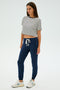 A person models SPLITS59's Sonja Fleece Sweatpant in Indigo, paired with a striped T-shirt and white sneakers, posed against a plain background. They look to the side, perfectly styled for cool-weather workouts.