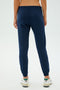 Rear view of a person wearing SPLITS59's Sonja Fleece Sweatpant in Indigo paired with white sneakers against a plain background, ready for workouts.