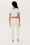 Person standing with their back to the camera, wearing an Airweight S/S Crop - White/Black by SPLITS59, matching joggers, and white sneakers.