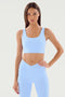 A woman in a light blue Sprint Rigor Bra - Skylight by SPLITS59 and matching leggings is standing against a plain background. She has one hand on her hip and is looking directly at the camera, showcasing the superior multi-sport performance of her ultra luxe workout attire.