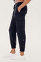 A person wearing SPLITS59 Supplex Cargo Pant - Black and white sneakers stands with hands in their pockets against a plain white background.