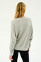 A person with long blonde hair is seen from the back, wearing the "Andie Fleece Sweatshirt - Heather Grey" by SPLITS59 and black pants against a plain white background.
