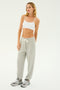 A person wearing a white crop top, the SPLITS59 Andie Oversized Fleece Sweatpant in Heather Grey, and grey sneakers stands against a plain white background, ready for cool weather workouts.