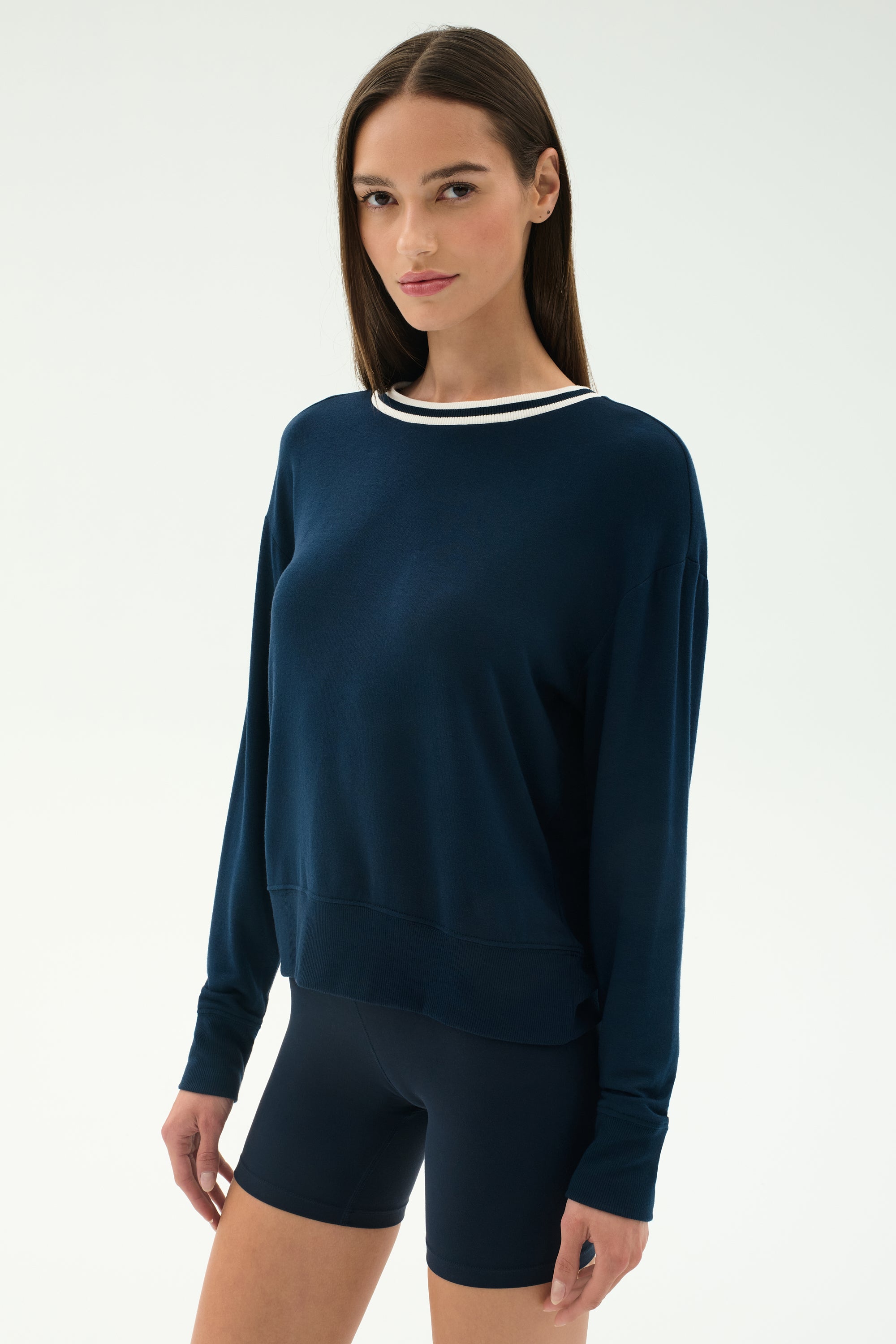 A person wears the SPLITS59 Sonja Fleece Sweatshirt W/ Stripe in indigo with matching shorts, featuring a white-striped collar, standing against a plain light background.