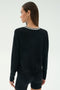 A woman with straight brown hair is seen from the back wearing the SPLITS59 Sonja Fleece Sweatshirt W/ Stripe in black, paired with black modal shorts, against a plain light background.
