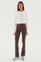 A person stands facing forward, wearing the Louise Rib Long Sleeve Crop - White by SPLITS59, brown fitted pants with white side stripes in a cropped style, and gray sneakers, against a plain, light-colored background. The ensemble seems perfect for gym workouts.