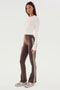 Woman dressed in a semi-fitted Louise Rib Long Sleeve Crop - White by SPLITS59 and brown flared pants with white side stripes, standing on a plain background, wearing gray sneakers.