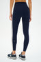 A person wearing SPLITS59 Clare High Waist Rigor 7/8 leggings in Dark Cherry/Creme, photographed from the back against a white background, paired with gray New Balance sneakers.