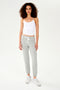 A woman wearing a SPLITS59 Loren Seamless Waist Length Tank in White with a shelf bra and grey sweatpants.