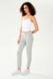 A woman wearing a SPLITS59 Loren Seamless Waist Length Tank in White with a built-in shelf bra and grey sweatpants.