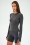 A person wearing the SPLITS59 Airweight Lite LS Waist Length in Graphite and black shorts with white stripes, designed for quick-dry comfort during gym workouts, stands against a plain background.