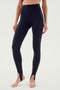 Person wearing SPLITS59's River High Waist Airweight Stirrup - Black leggings with stirrup straps at the ankles, a perfect choice for hot yoga, standing barefoot against a plain background.