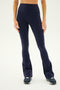 A person wearing the SPLITS59 Raquel High Waist Flared Legging in Indigo and black sneakers stands against a white background.