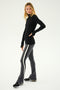 A person stands against a plain background, wearing a black long-sleeve top and SPLITS59's Raquel High Waist Flared Legging in Heather Grey with white and black stripes down the sides. The high waist leggings showcase their form perfectly, while their black and white sneakers complete the look.