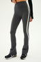A person wearing SPLITS59's Raquel High Waist Flared Legging in Heather Grey with white and black accents, paired with black and white sneakers and a black long-sleeve top.