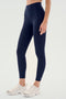 A person wearing SPLITS59's Airweight High Waist Legging in Indigo and white sneakers, standing against a plain background.