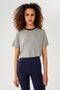Front view of girl wearing  light grey cropped short sleeve t-shirt with thin dark blue neck hem and dark blue leggings 