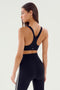 A woman with long hair is seen from behind, wearing the SPLITS59 Ella Airweight Bra in Black/White and airweight leggings with side stripes, perfect for hot yoga sessions.